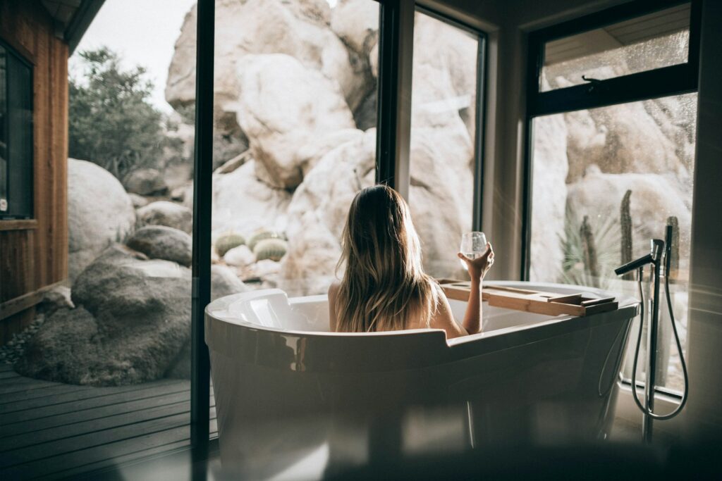 femme dans une baignoire blanche tenant un verre transparent