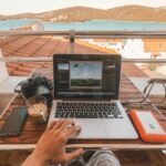 person holding MacBook Pro besides orange power bank